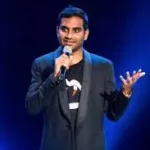 Aziz Ansari with black sports coat doing standup.