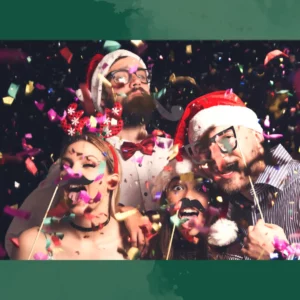 Two men and two girls doing a funny pose for a picture with a Santa hat and mustache props surrounded by confetti.