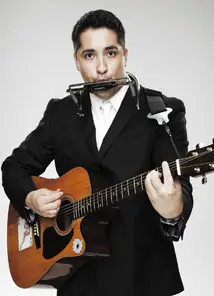 Hispanic Comedian for hire with guitar and harmonica in a black suit.