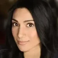 Female Indian-American stand-up comic with long black hair looking at the camera.