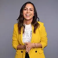Anjelah Johnson-Rejes is a female hispanic comedian in a yellow jacket and white shirt.